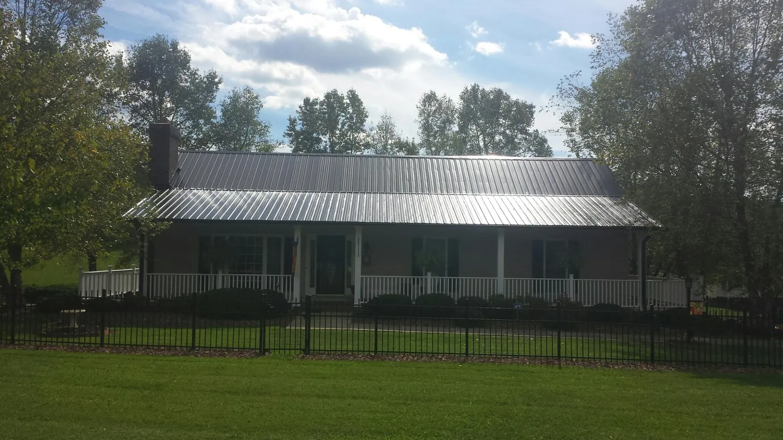 Gray metal roof on a brick ranch with a full width front porch — Gutter Guard Installation work by our crew in Jupiter