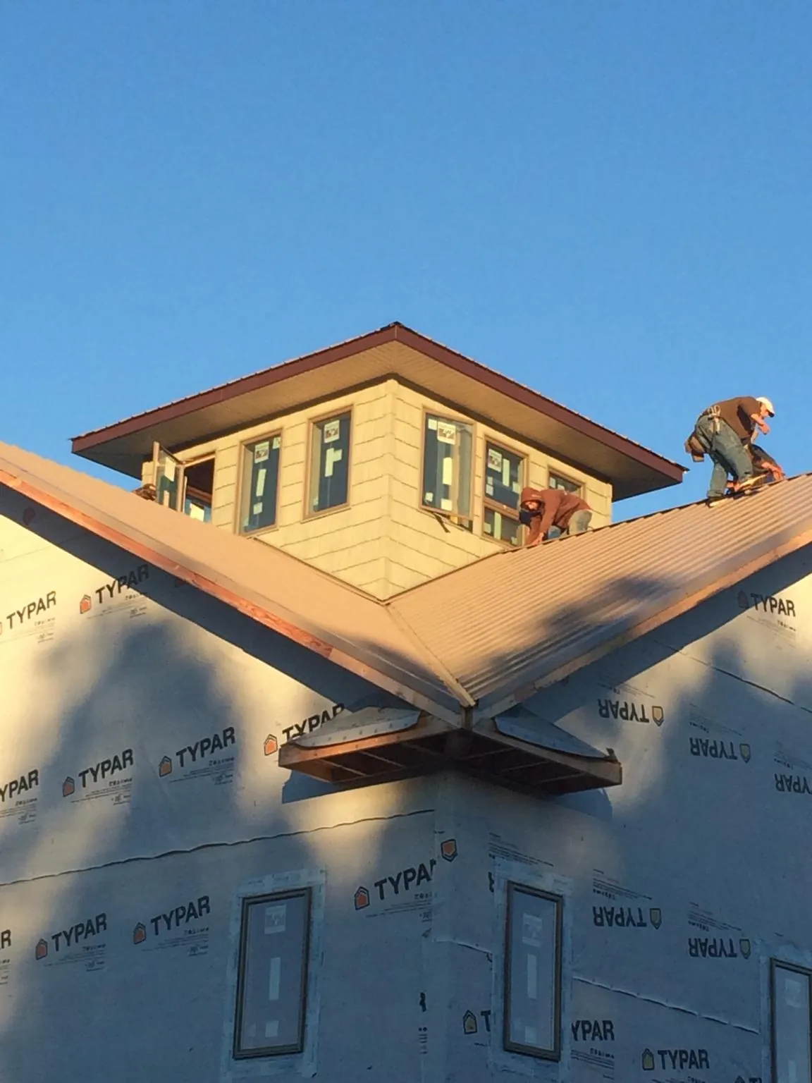 Roofers working around a rooftop cupola on a new metal roof at sunset — Roof Waterproofing in Jupiter by Roofing Brothers